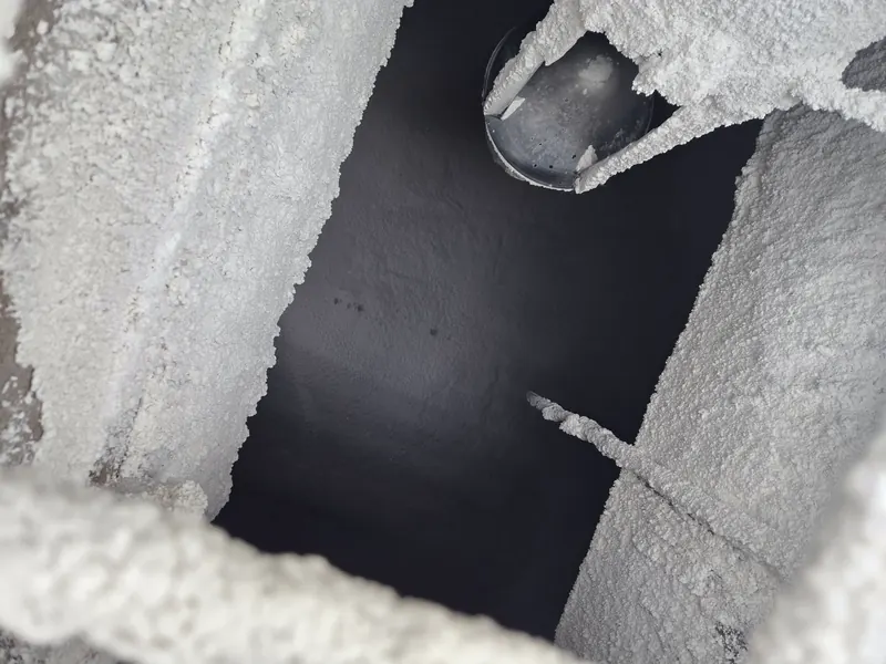 Looking into a salt-encrusted bunker interior — heavy white crystallization on the walls and discharge cone shows the harsh atmosphere OWL EYE® BUNKERS sensors operate in