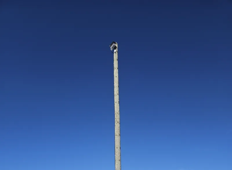 OWL EYE® stockpile sensor mounted high on a treated wooden pole above a limestone quarry — long-range LiDAR for open-pit monitoring